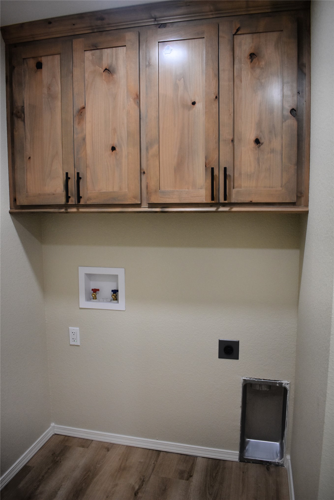 2915 East 2090 Road, Unit LOT 1 Hugo, OK 74743 - Photo 15 of 28 Laundry area featuring wood-finish flooring, overhead cabinetry with matte black hardware, and utility hookups