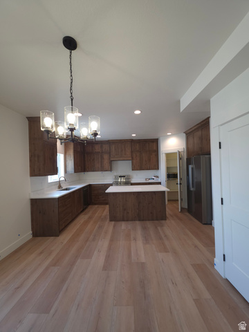 1267 West 2350 South Perry, UT 84302 - Photo 4 of 20 Open-concept kitchen featuring wood-finish flooring, dark wood cabinetry, white countertops, a central island, and stainless steel appliances