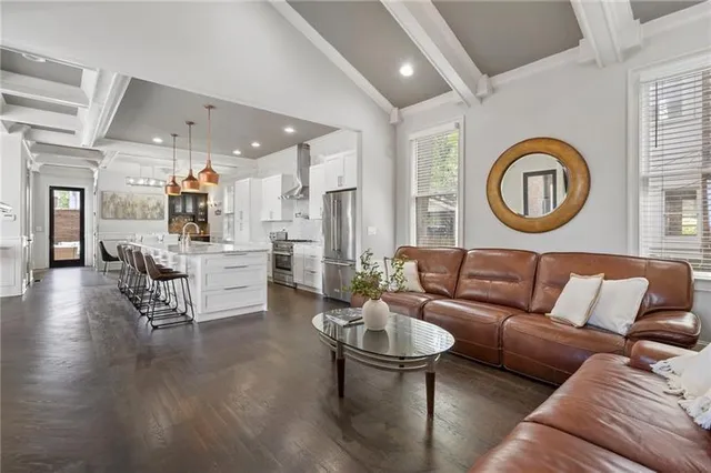 a kitchen with stainless steel appliances kitchen island granite countertop a refrigerator a stove a dining table and chairs with wooden floor