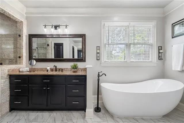 a bathroom with a granite countertop sink a mirror and shower