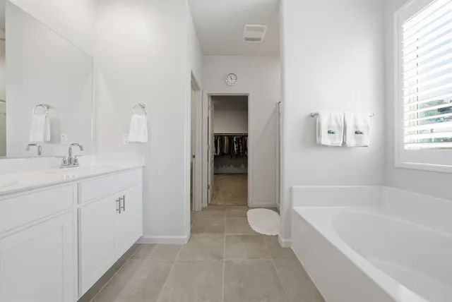 a spacious bathroom with a tub sink and mirror