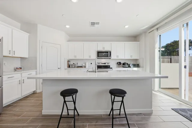 a kitchen with stainless steel appliances a table chairs refrigerator and cabinets