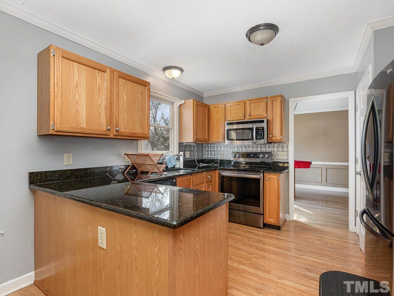 2512 Holbrook Court Raleigh, NC 27604 - Photo 12 of 26 a kitchen with stainless steel appliances granite countertop a stove a sink dishwasher a microwave oven and a refrigerator with wooden floor