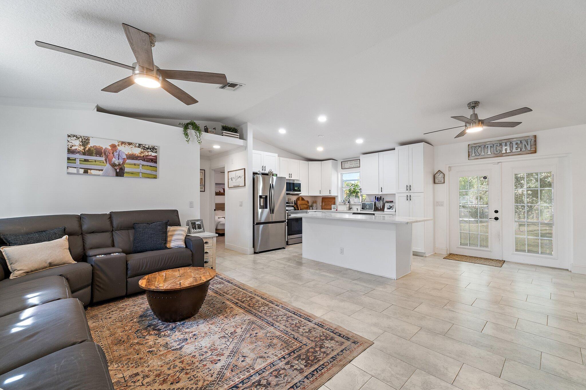 18389 41st Road North Loxahatchee, FL 33470 - Photo 6 of 33 a large living room with stainless steel appliances kitchen island granite countertop a couch and white cabinets