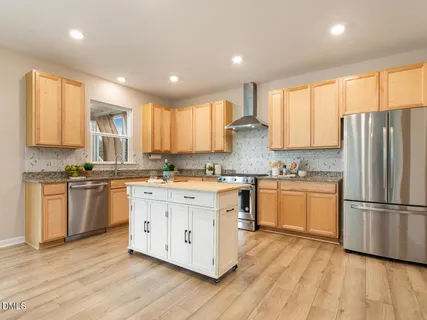 a kitchen with stainless steel appliances granite countertop a refrigerator a sink dishwasher a stove and white cabinets with wooden floor