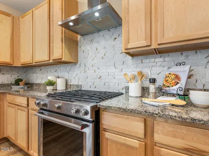 a kitchen with granite countertop stainless steel appliances a stove a sink and cabinets