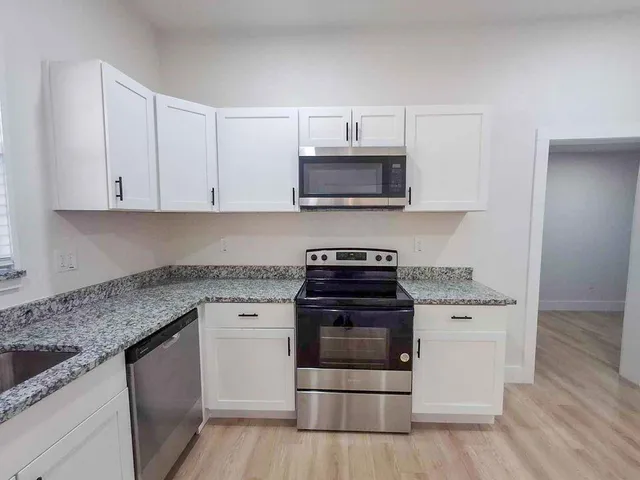 a kitchen with white cabinets and appliances