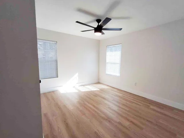 a view of empty room with wooden floor and fan