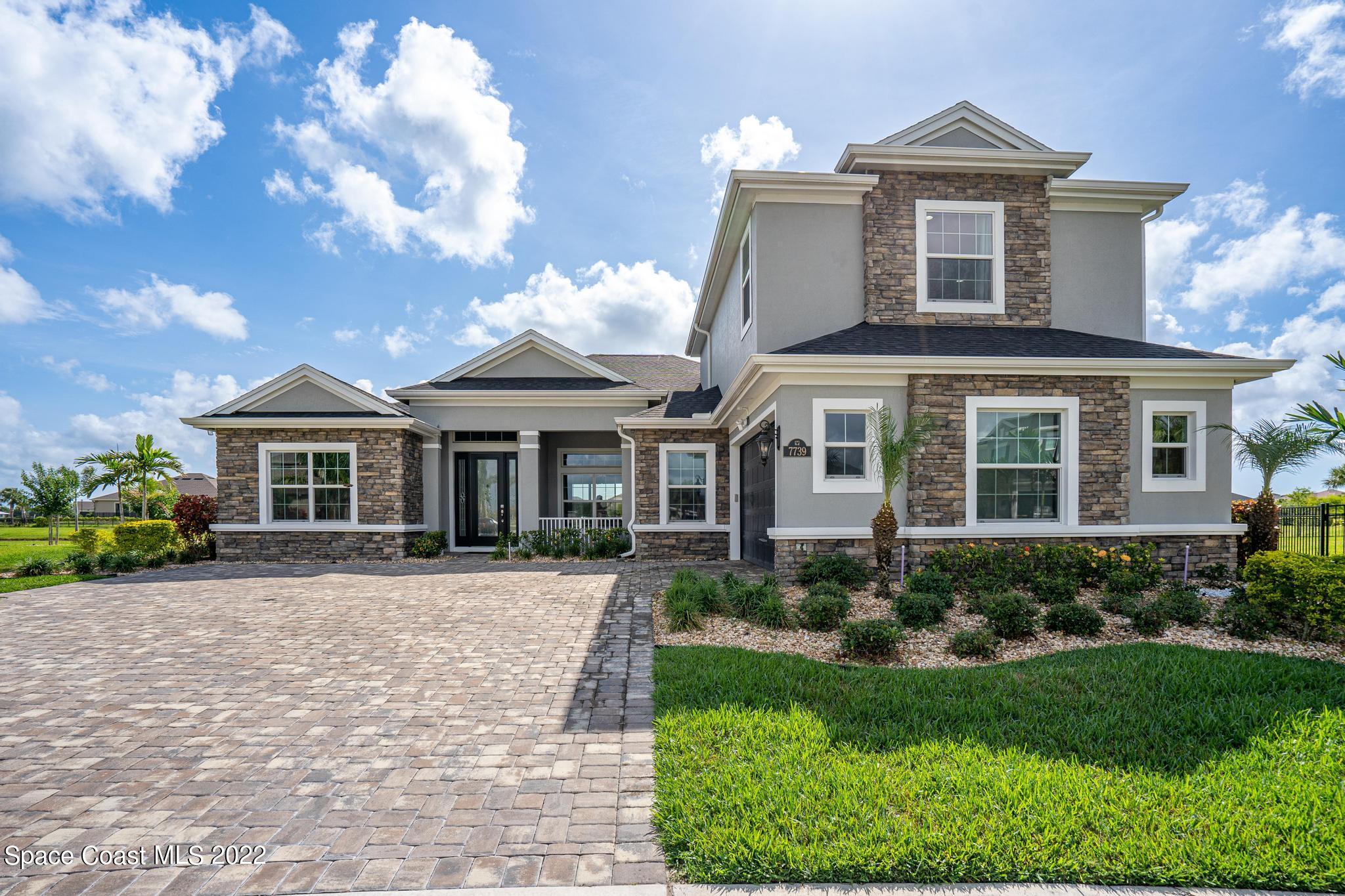 a front view of a house with a yard and potted plants