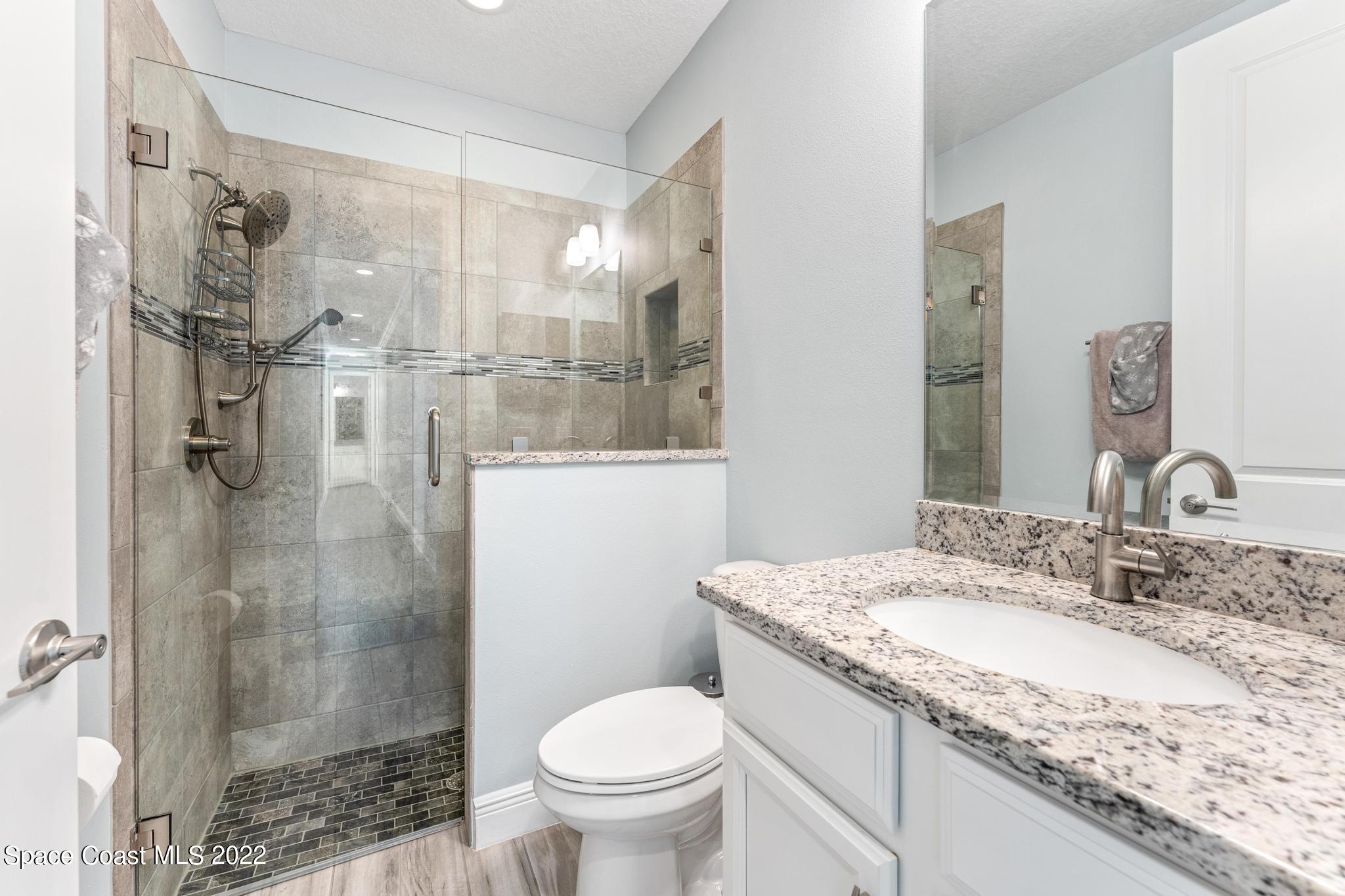 7739 Kerrington Drive Melbourne, FL 32940 - Photo 15 of 35 a bathroom with a granite countertop sink toilet and shower