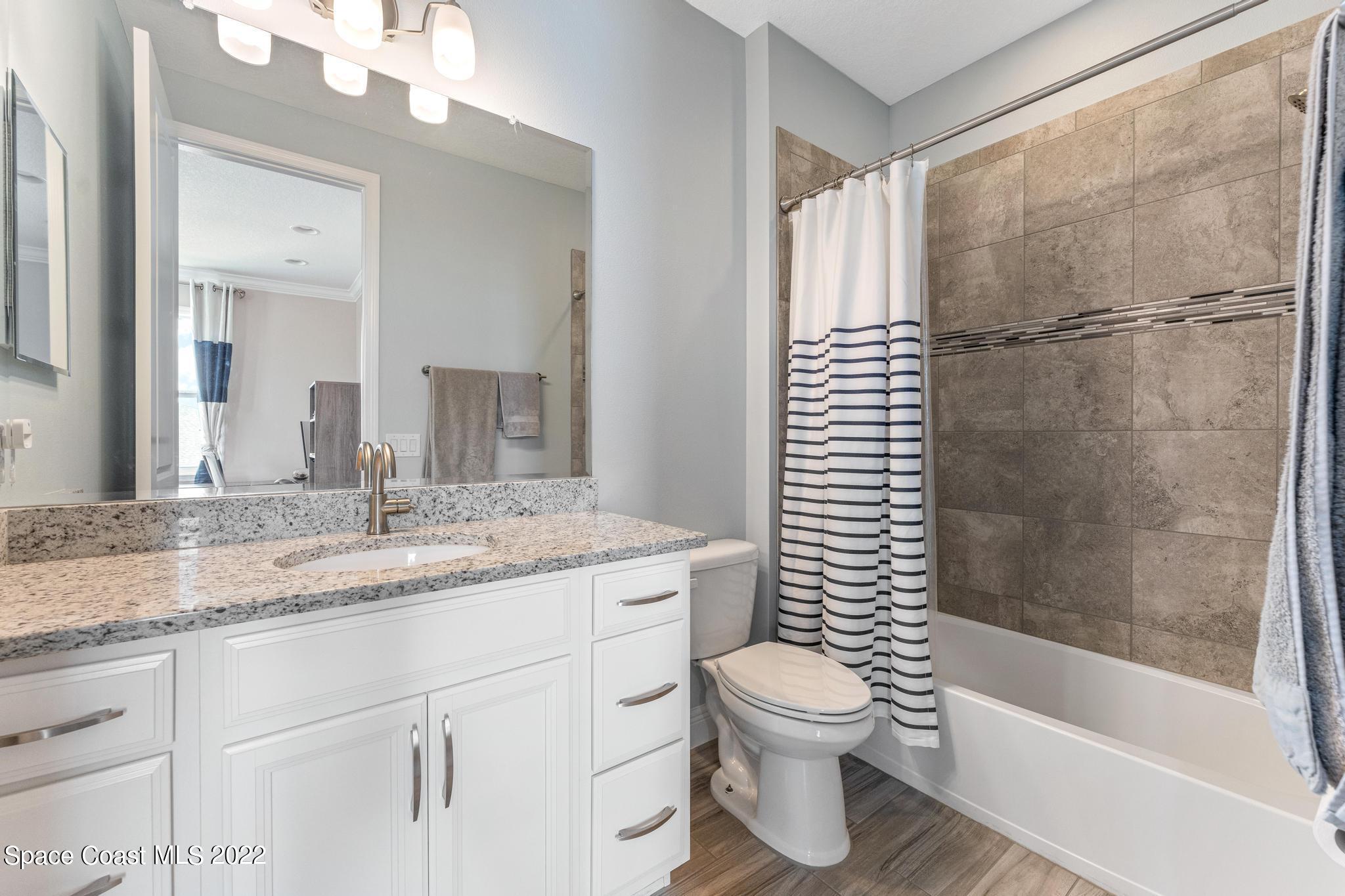 7739 Kerrington Drive Melbourne, FL 32940 - Photo 19 of 35 a bathroom with a granite countertop sink toilet and shower