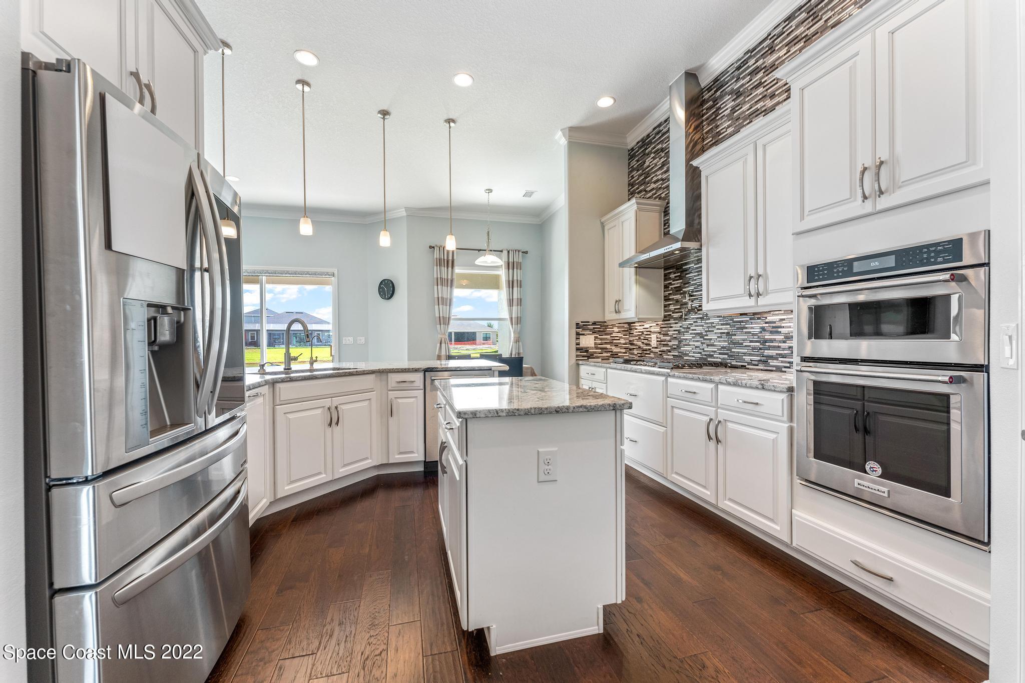 7739 Kerrington Drive Melbourne, FL 32940 - Photo 6 of 35 a kitchen with white cabinets and stainless steel appliances