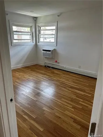 a view of empty room with window and wooden floor