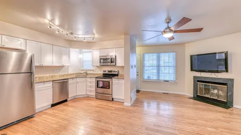 a kitchen with granite countertop a stove a refrigerator a sink dishwasher with a fireplace and wooden floor