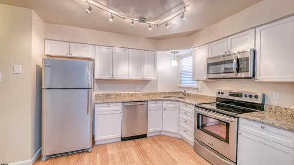 a kitchen with stainless steel appliances granite countertop a refrigerator a stove top oven a sink and dishwasher