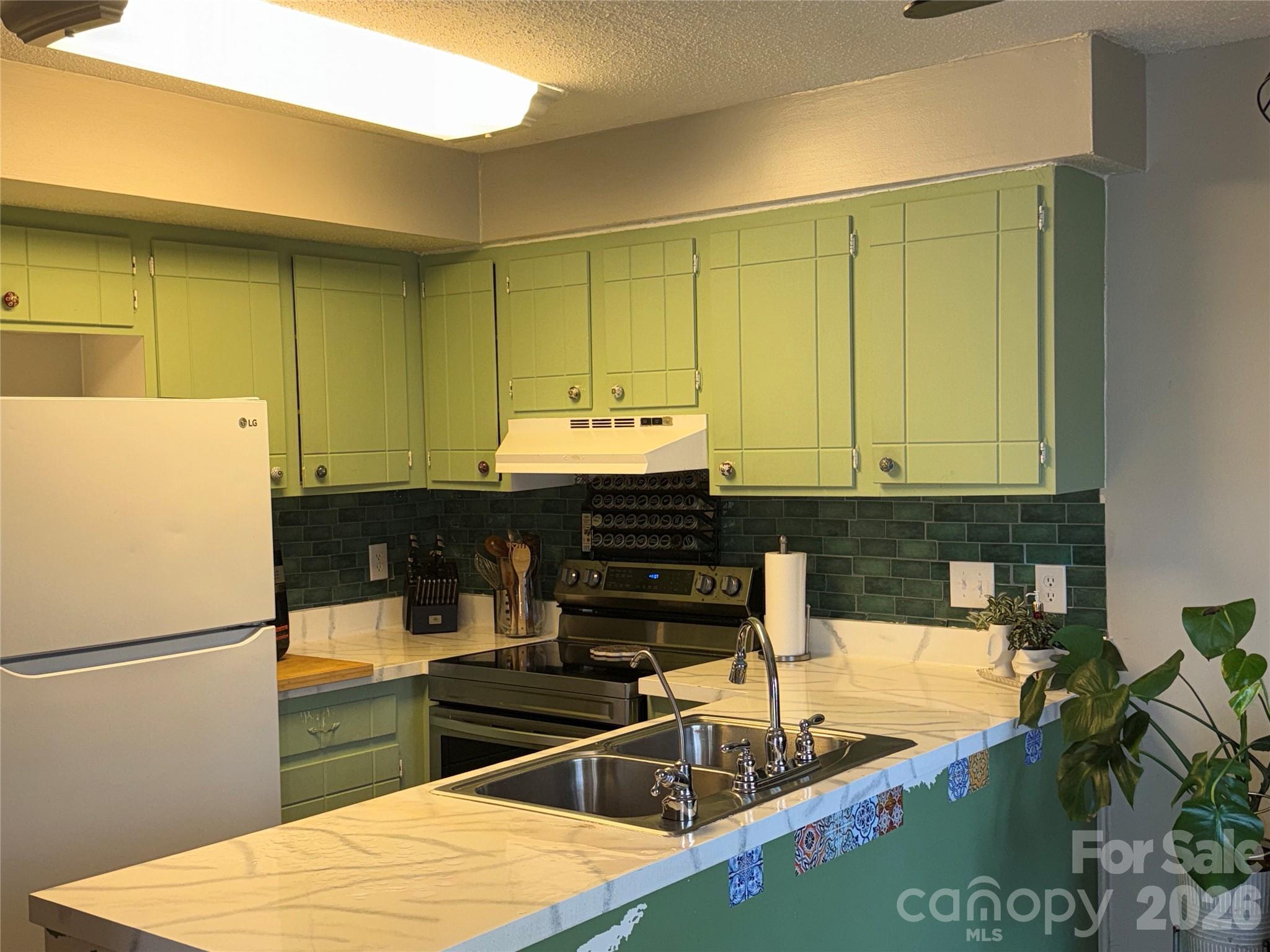 1304 Seaton Road, Unit 15 Durham, NC 27713 - Photo 6 of 20 a kitchen with kitchen island a stove a sink and a refrigerator