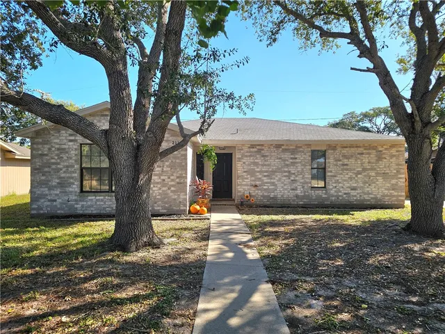 a front view of a house with a yard and large tree