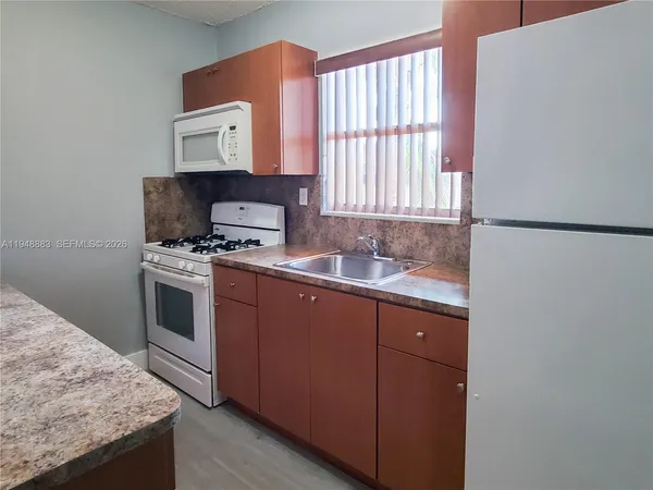 a kitchen with granite countertop white cabinets and white appliances