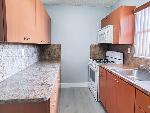 a kitchen with granite countertop a sink a stove and cabinets