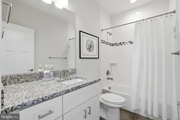a bathroom with a granite countertop sink toilet and a mirror