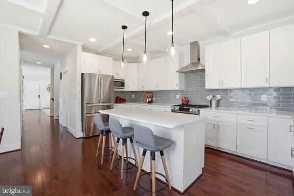 a kitchen with stainless steel appliances granite countertop a refrigerator a sink dishwasher a stove and white cabinets with wooden floor