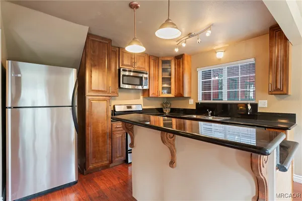 a kitchen with stainless steel appliances granite countertop a refrigerator a sink dishwasher a stove and a refrigerator