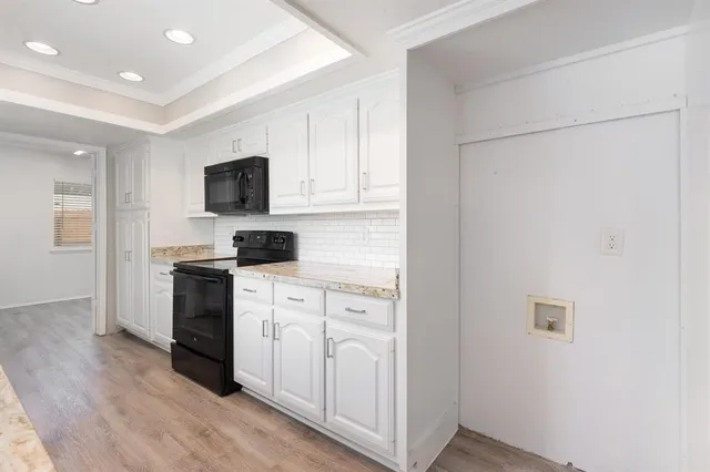 a kitchen with white cabinets and black appliances