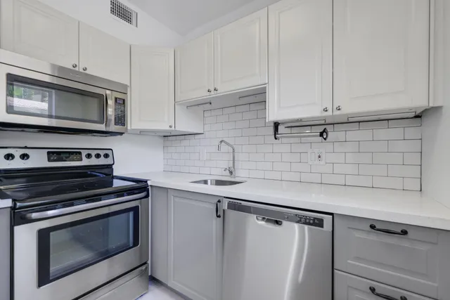 a kitchen with white cabinets and stainless steel appliances