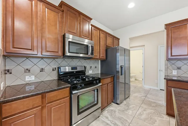 a kitchen with granite countertop a stove a microwave a sink and cabinets