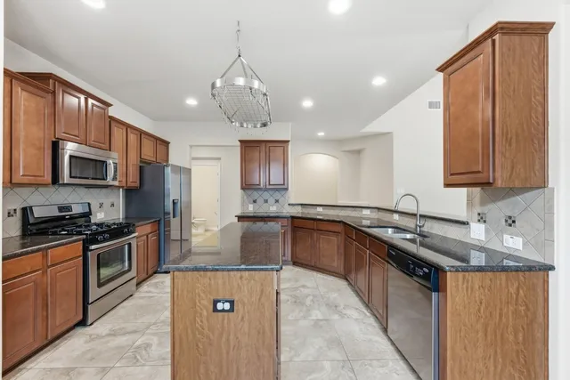 a kitchen with stainless steel appliances granite countertop a sink stove and refrigerator