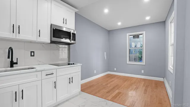 a kitchen with white cabinets and sink