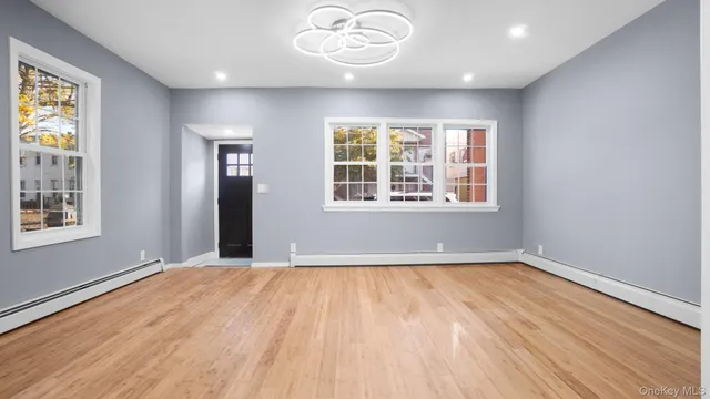 a view of an empty room with a window and wooden floor