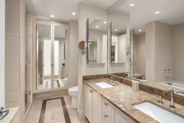 a bathroom with a granite countertop sink a toilet a large mirror and shower