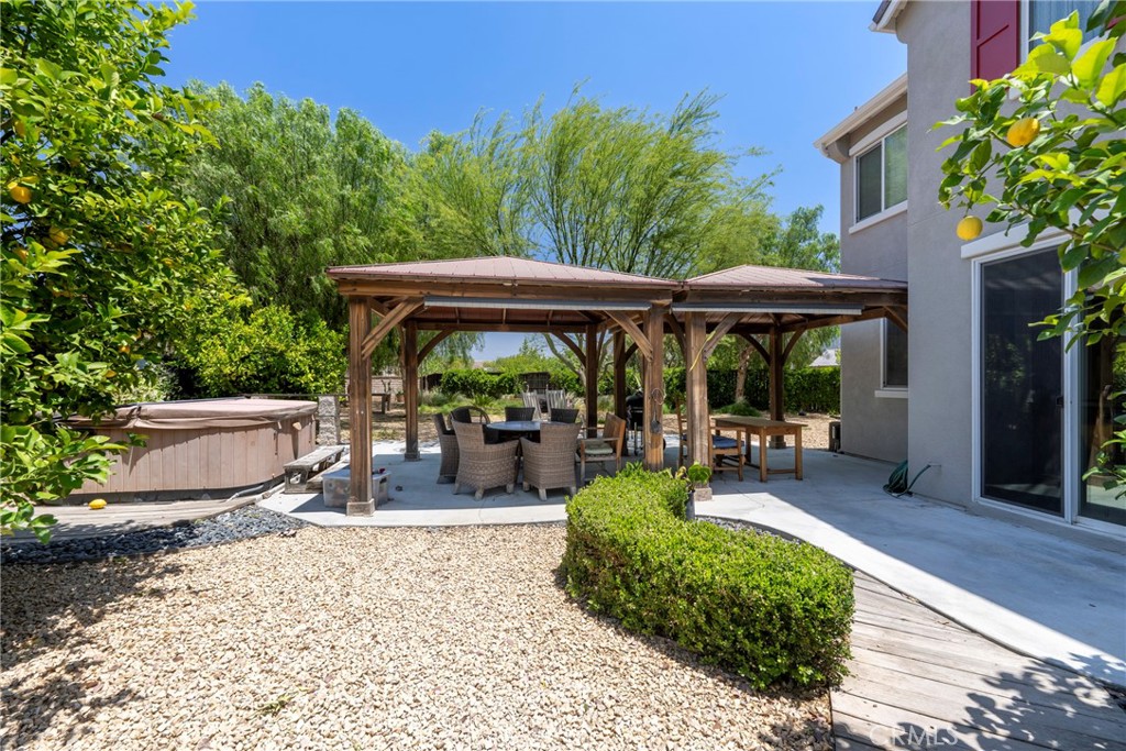 3819 St Austell Way Perris, CA 92571 - Photo 49 of 64 a view of a patio with table and chairs potted plants and large tree