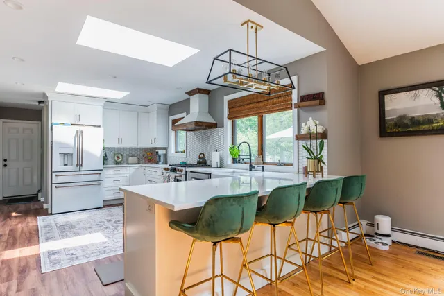 a kitchen with stainless steel appliances a dining table chairs stove refrigerator and cabinets