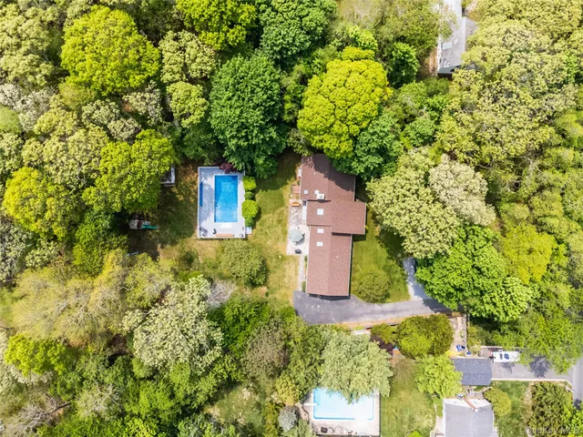 an aerial view of a house with a yard and large trees