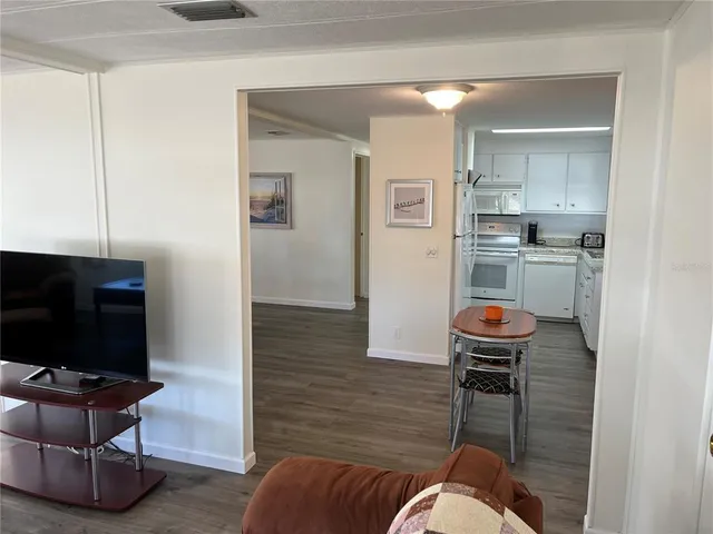 a living room with furniture a flat screen tv and kitchen view