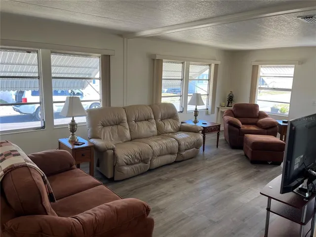 a living room with furniture a flat screen tv and windows