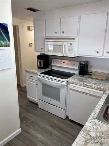 a kitchen with granite countertop white cabinets and white appliances