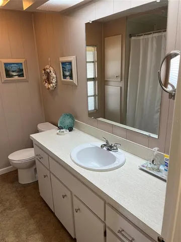 a bathroom with a granite countertop sink toilet and mirror