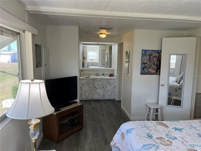 a bedroom with a bed and a flat tv screen on dresser