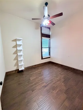 an empty room with wooden floor chandelier fan and windows