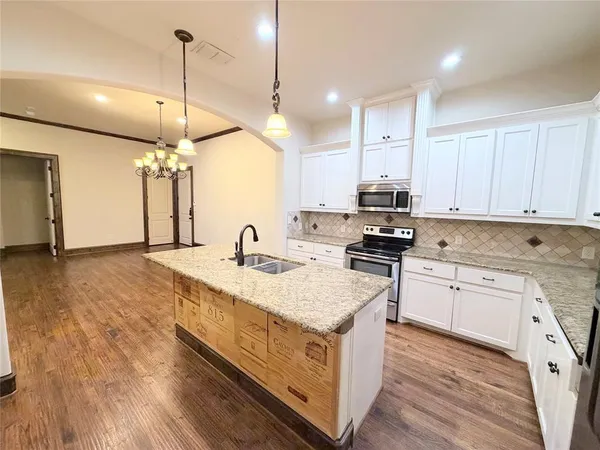 a kitchen with stainless steel appliances granite countertop a sink a stove and a wooden floors