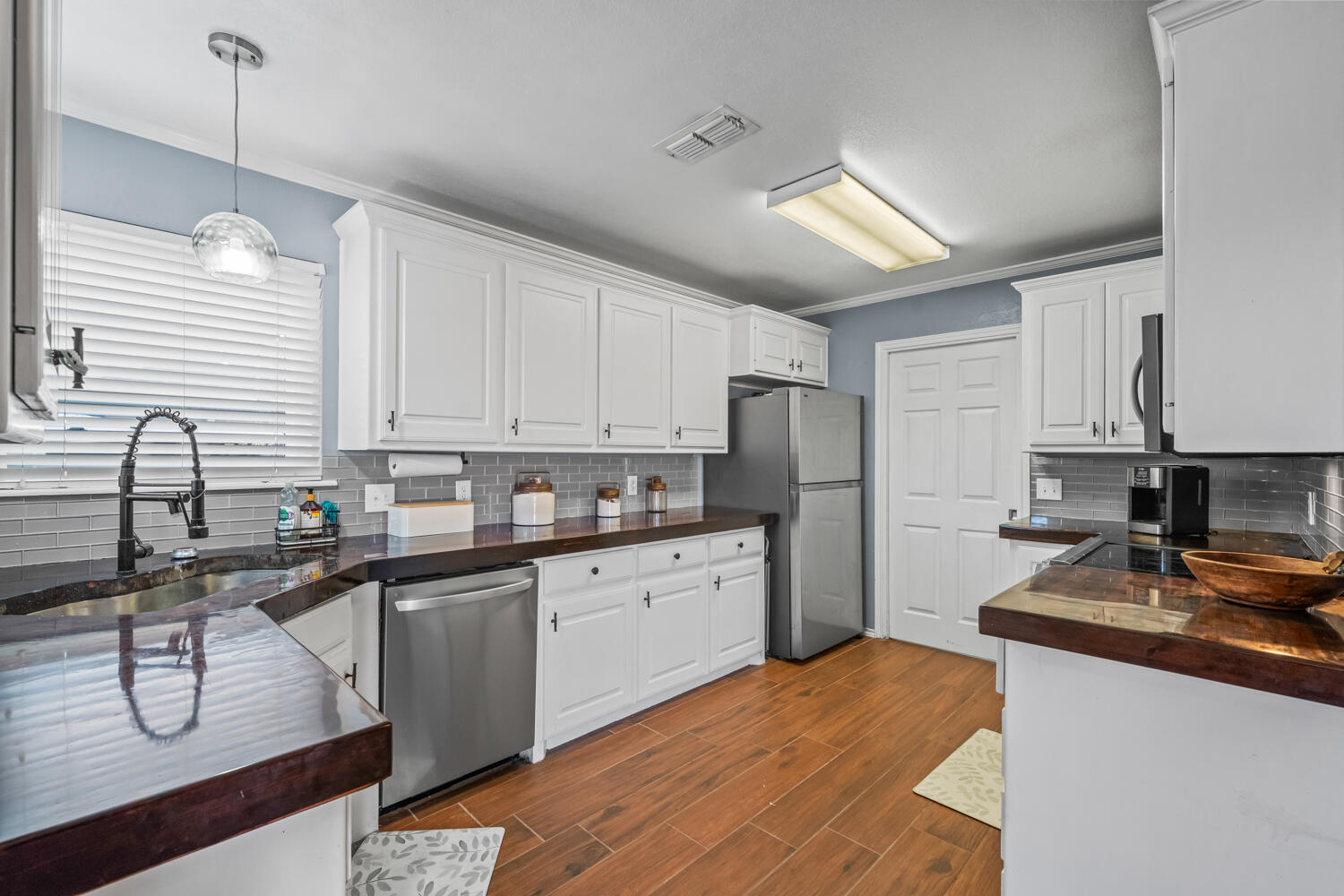 2605 Madison Street Lubbock, TX 79415 - Photo 6 of 23 a kitchen with stainless steel appliances granite countertop a sink dishwasher a refrigerator and white cabinets with wooden floor