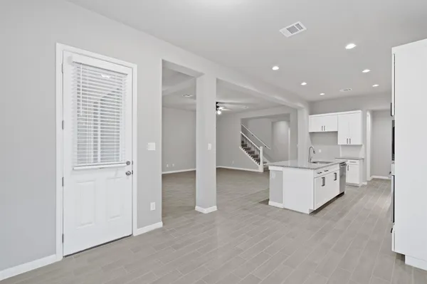 a large white kitchen with kitchen island a sink wooden floor and a refrigerator