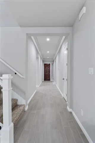 a view of a hallway with wooden floor and a bathroom