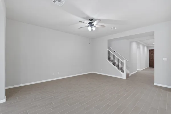 an empty room with wooden floor fan and windows