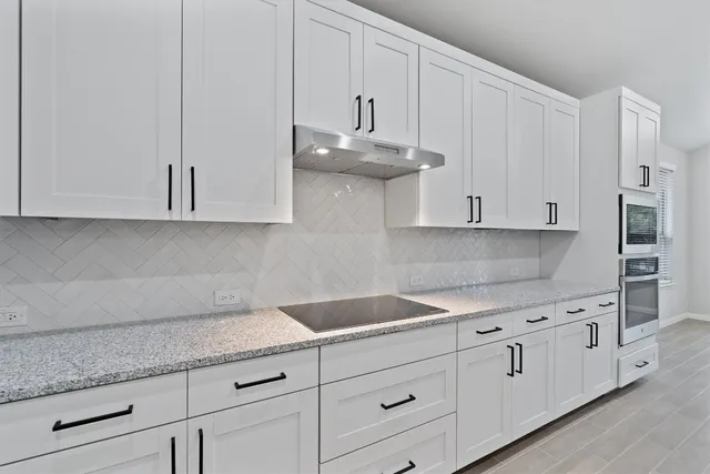 a kitchen with granite countertop white cabinets and stainless steel appliances