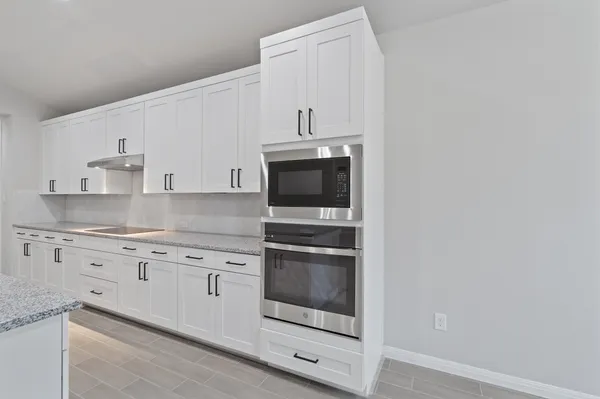 a kitchen with granite countertop white cabinets and stainless steel appliances