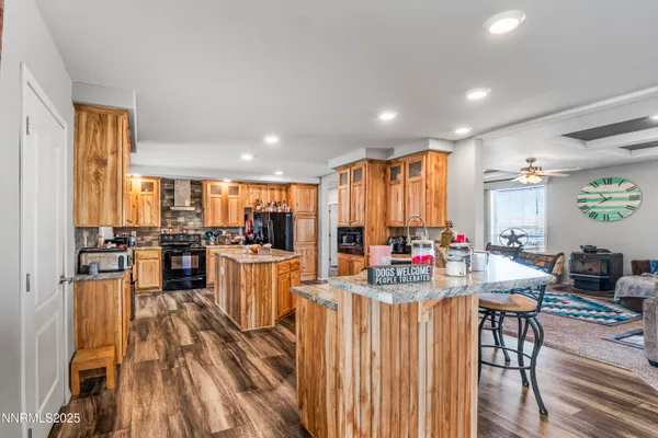 a kitchen with stainless steel appliances kitchen island granite countertop a refrigerator a stove a sink dishwasher a couches with wooden cabinets and wooden floor
